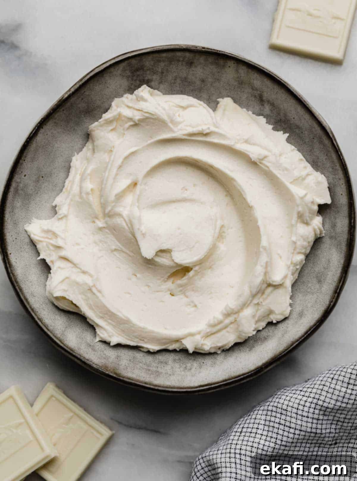 Luscious White Chocolate Frosting 7 A stylish gray bowl generously filled with freshly made, incredibly smooth White Chocolate Buttercream Frosting, ready for any sweet creation.