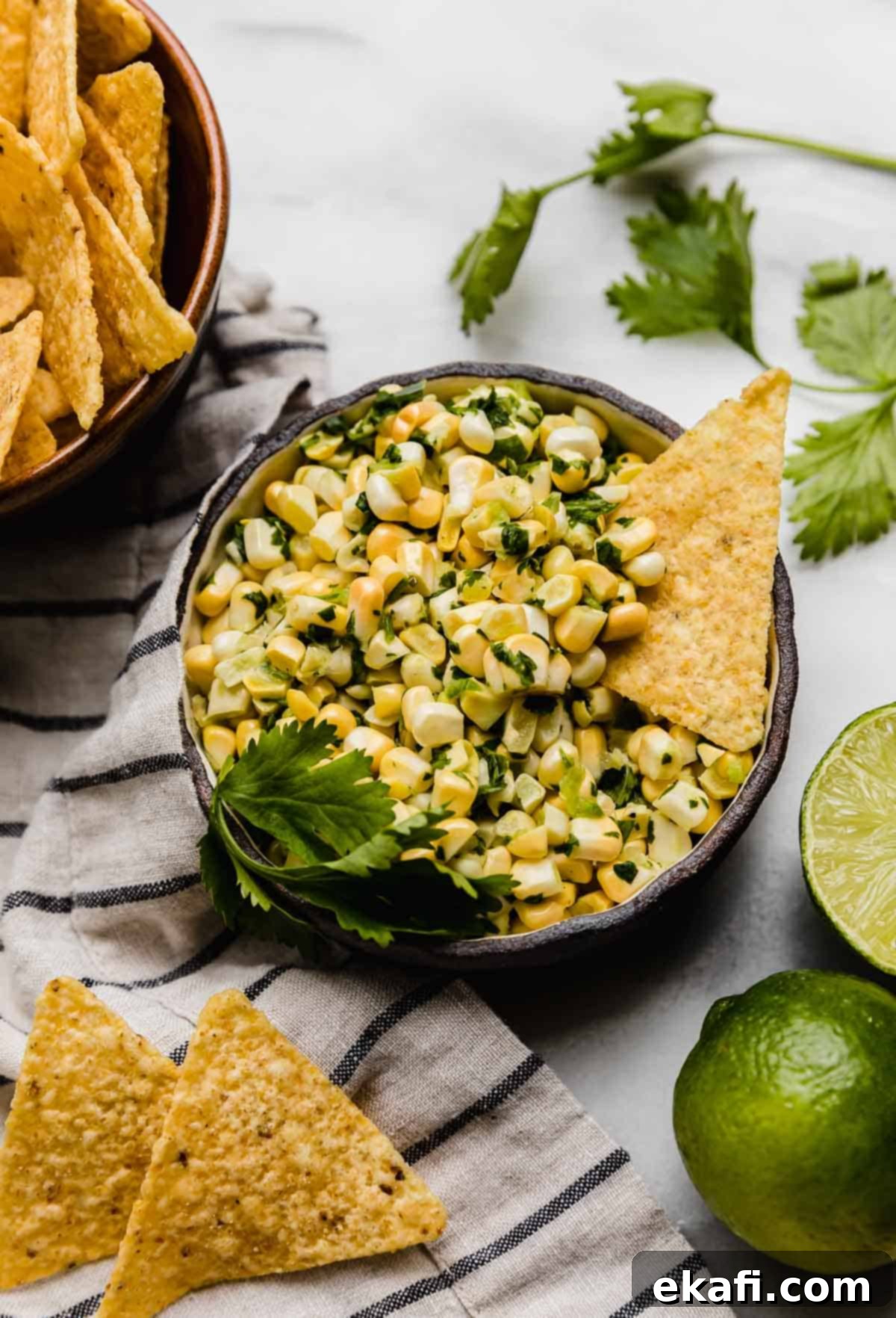 Summer Corn Salsa 2 A black bowl filled with Fresh Corn Salsa with jalapeño and cilantro on a white background.