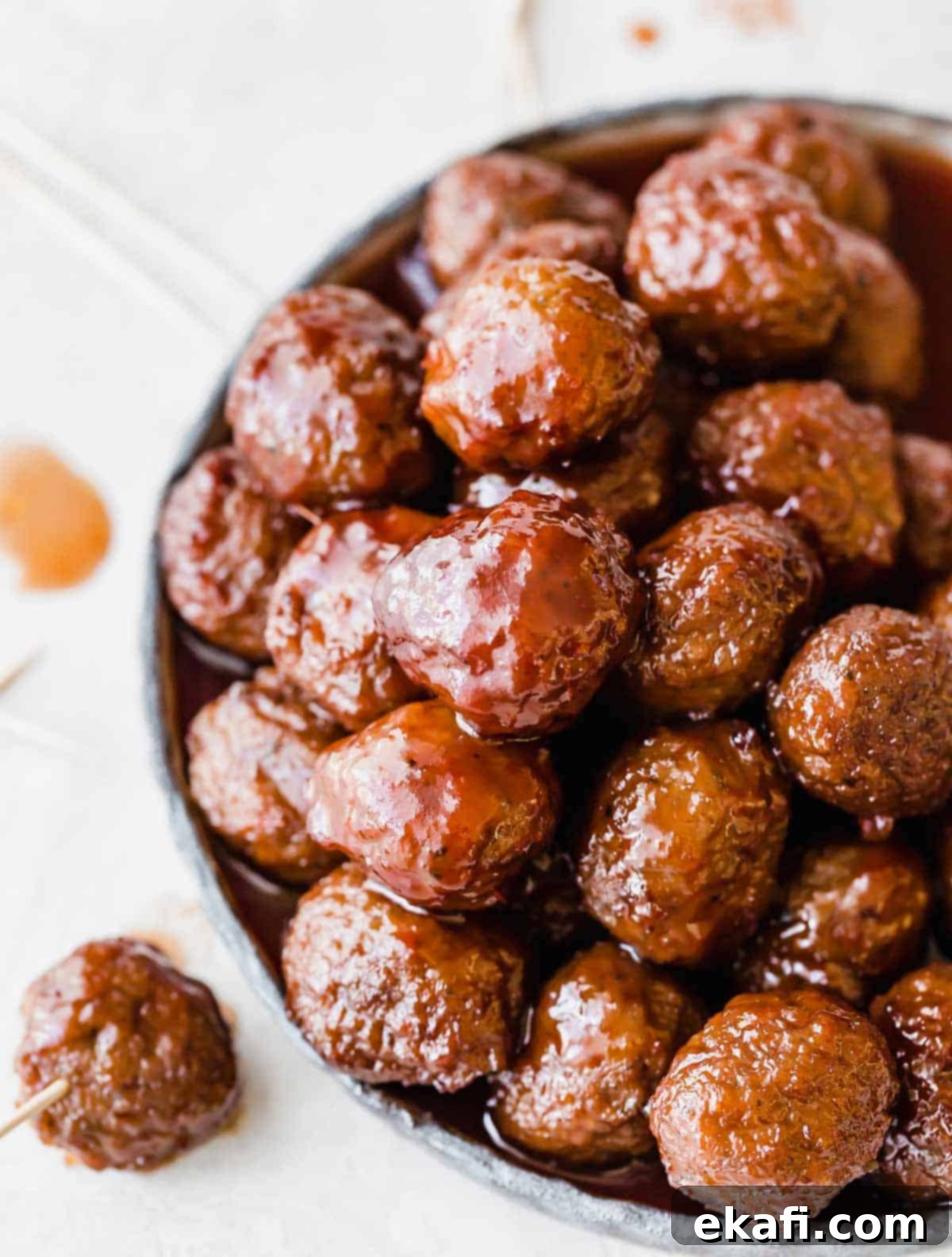 Sweet and Tangy Slow Cooker Meatballs 5 Overhead photo of Grape Jelly Meatballs on a plate against a white background, garnished with parsley.