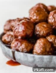 Sweet and Tangy Slow Cooker Meatballs 7 Crock pot Grape Jelly Meatballs on a black plate against a white background.