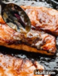 Caramelized Brown Sugar Salmon 8 A spoon drizzling rich brown sugar and butter glaze over a beautifully seared salmon fillet, creating a tempting sheen.