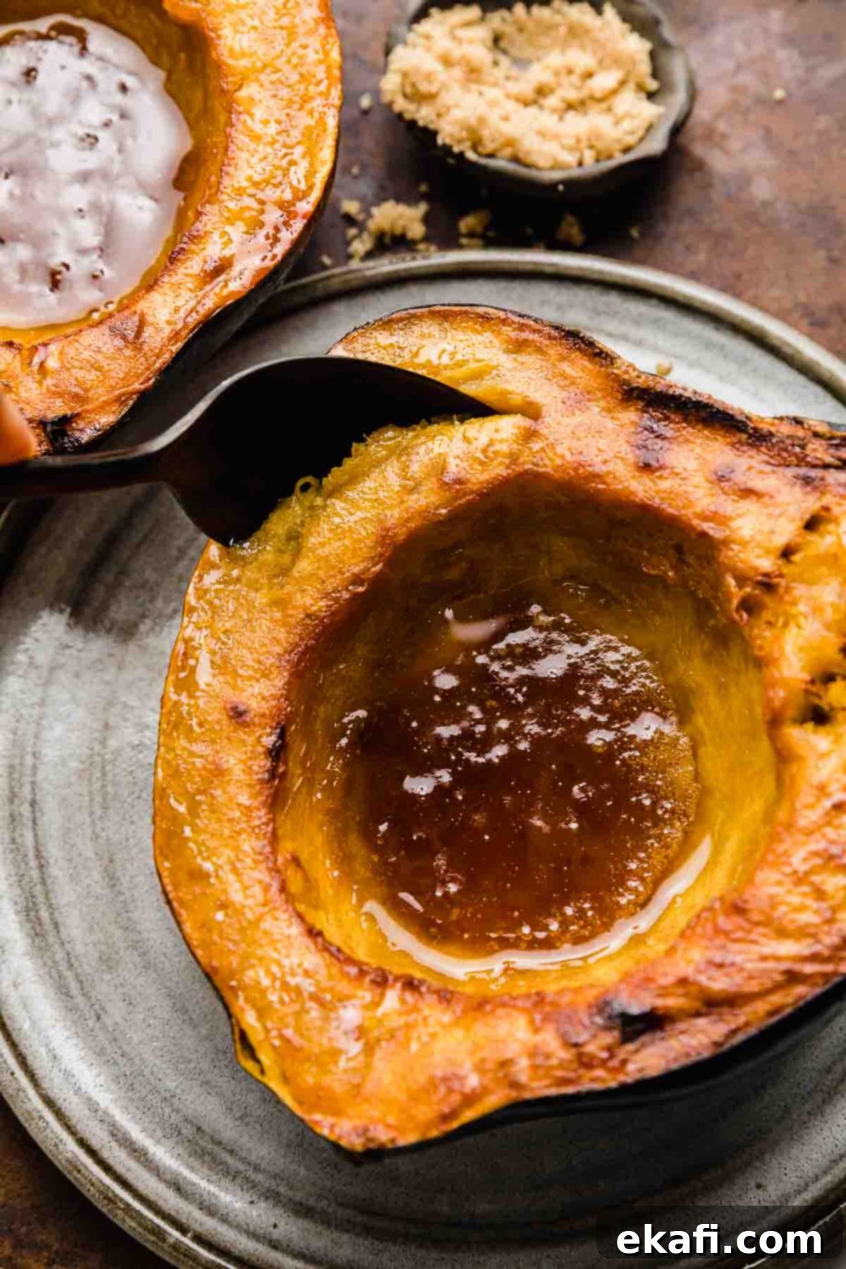 Caramelized Brown Sugar Acorn Squash 2 Roasted acorn squash with buttery brown sugar in the center of the squash, and a spoon scooping out the squash flesh.