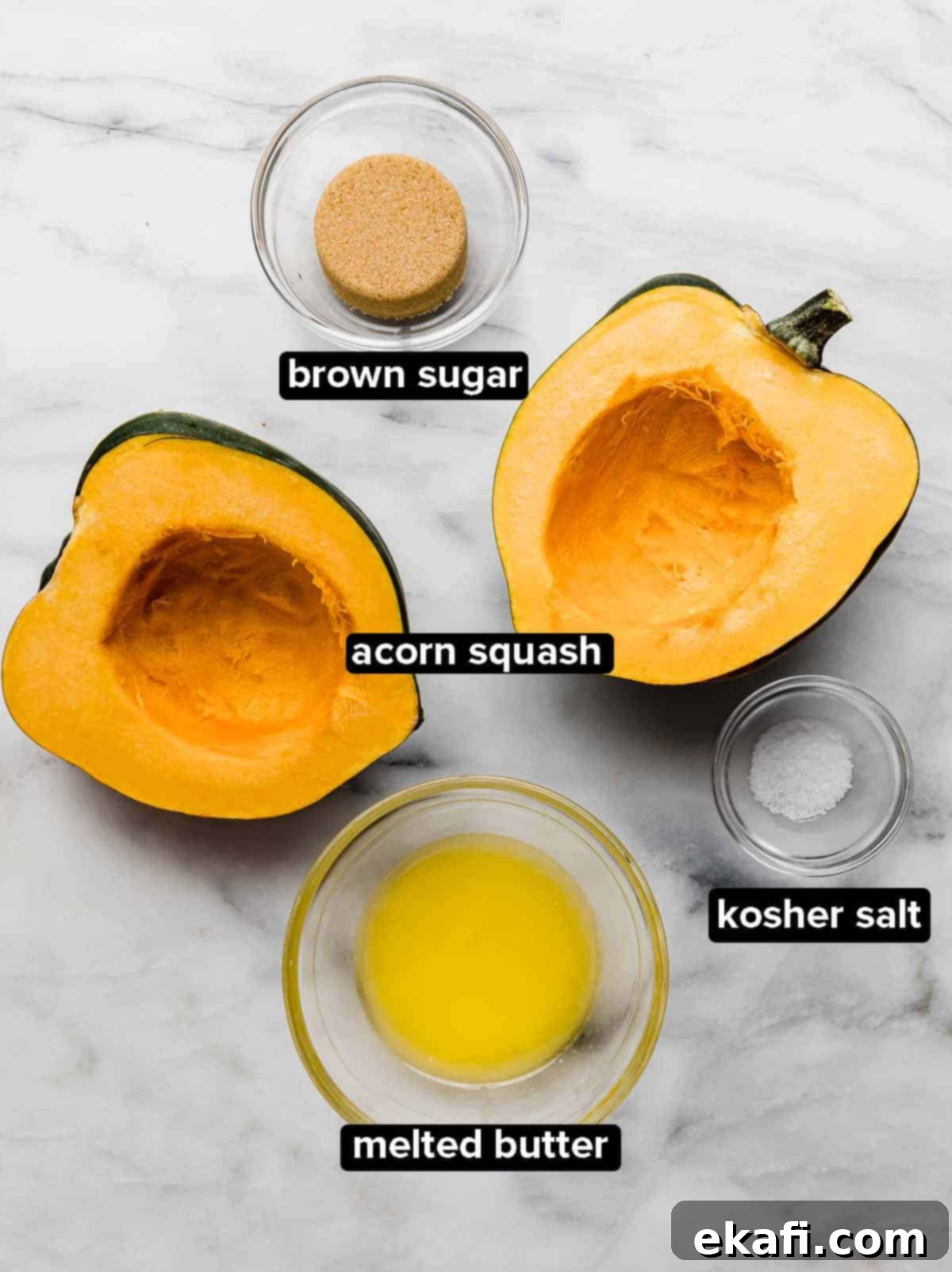 Caramelized Brown Sugar Acorn Squash 3 Brown Sugar Acorn Squash ingredients on a white marble background: acorn squash cut in half, salt, butter, and brown sugar.