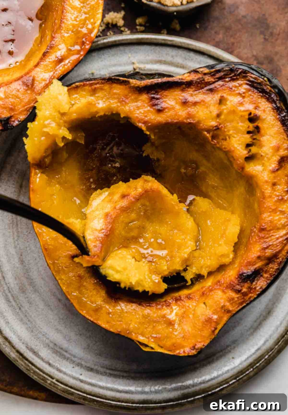 Caramelized Brown Sugar Acorn Squash 5 A spoon scooping out orange flesh from a bon bon winter squash with brown sugar.