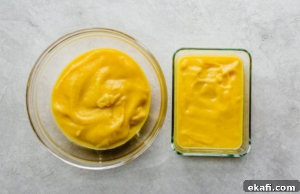 Tropical Mango Freeze 6 Two glass bowls filled with smooth mango sorbet puree. One bowl is significantly smaller, containing about one cup, while the other holds the remaining larger portion. They are sitting on a light-colored surface.