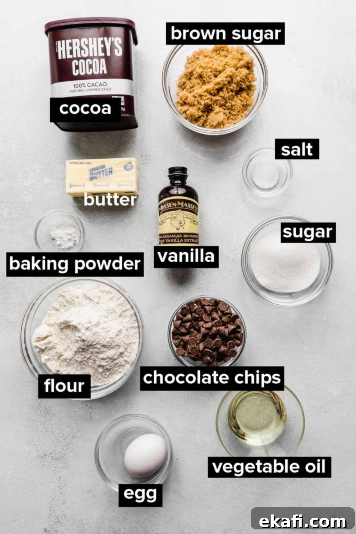 Fudgy Brownie Cookies 3 A collection of essential ingredients laid out on a clean surface, ready for making fudgy brownie cookies, including cocoa powder, sugars, butter, oil, eggs, and flour.