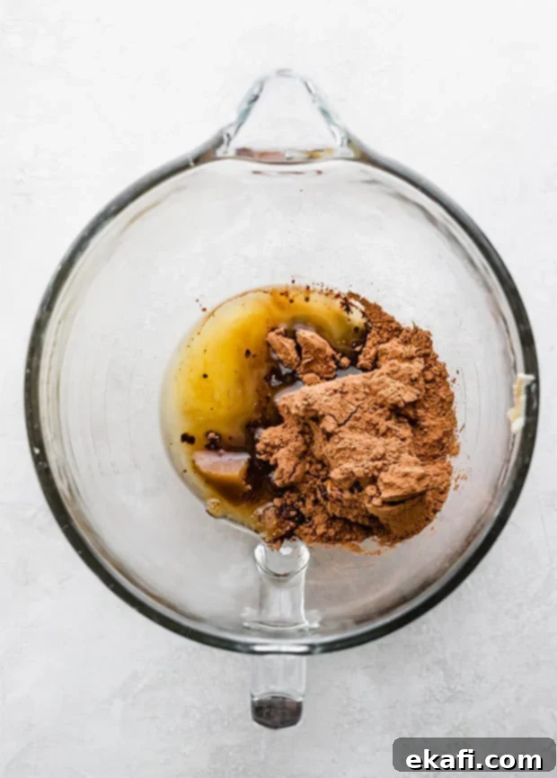 Fudgy Brownie Cookies 4 A glass bowl containing a rich, dark mixture of cocoa, melted butter, sugars, and oil, perfectly combined and ready for the next steps in preparing brownie cookie dough.