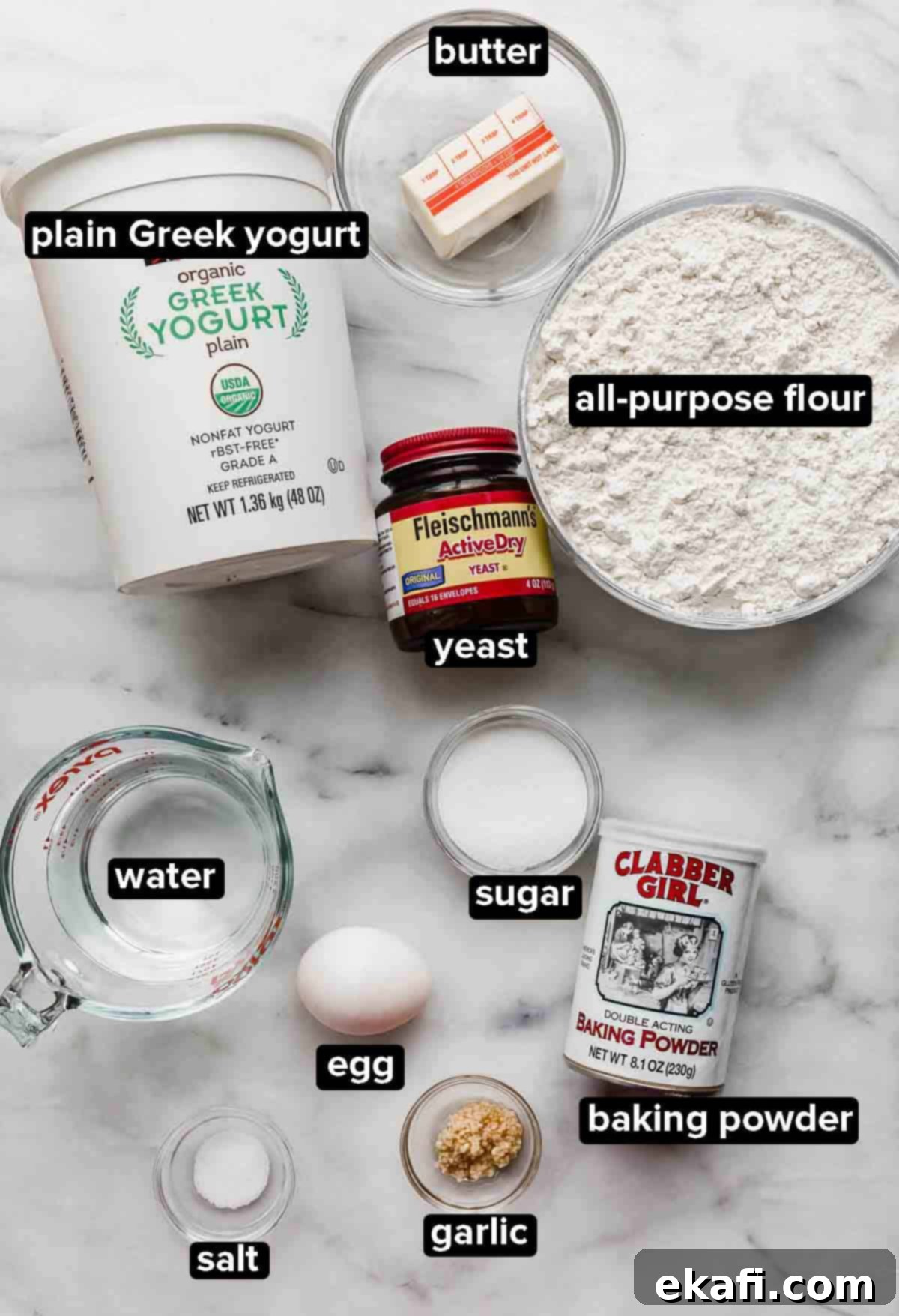 Pillowy Greek Yogurt Naan 3 Greek Yogurt Naan Bread ingredients on a white background: yeast, flour, butter, plain greek yogurt, water, egg, garlic, and baking powder, laid out neatly for a recipe.