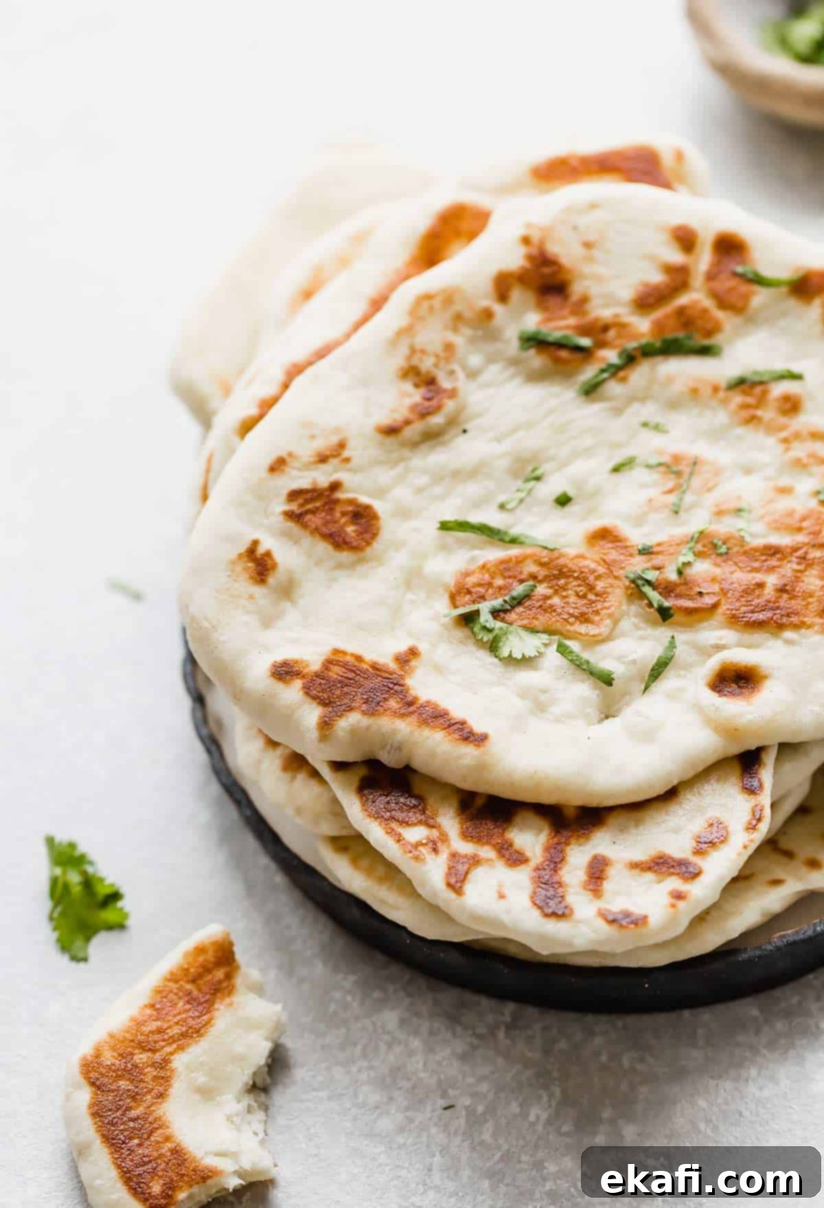Pillowy Greek Yogurt Naan 7 Fluffy homemade naan bread made with yeast and Greek yogurt, on a white background, ready to be served.