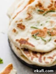 Pillowy Greek Yogurt Naan 8 Golden brown cooked Greek Yogurt Naan Bread on a black plate, fresh from the skillet.
