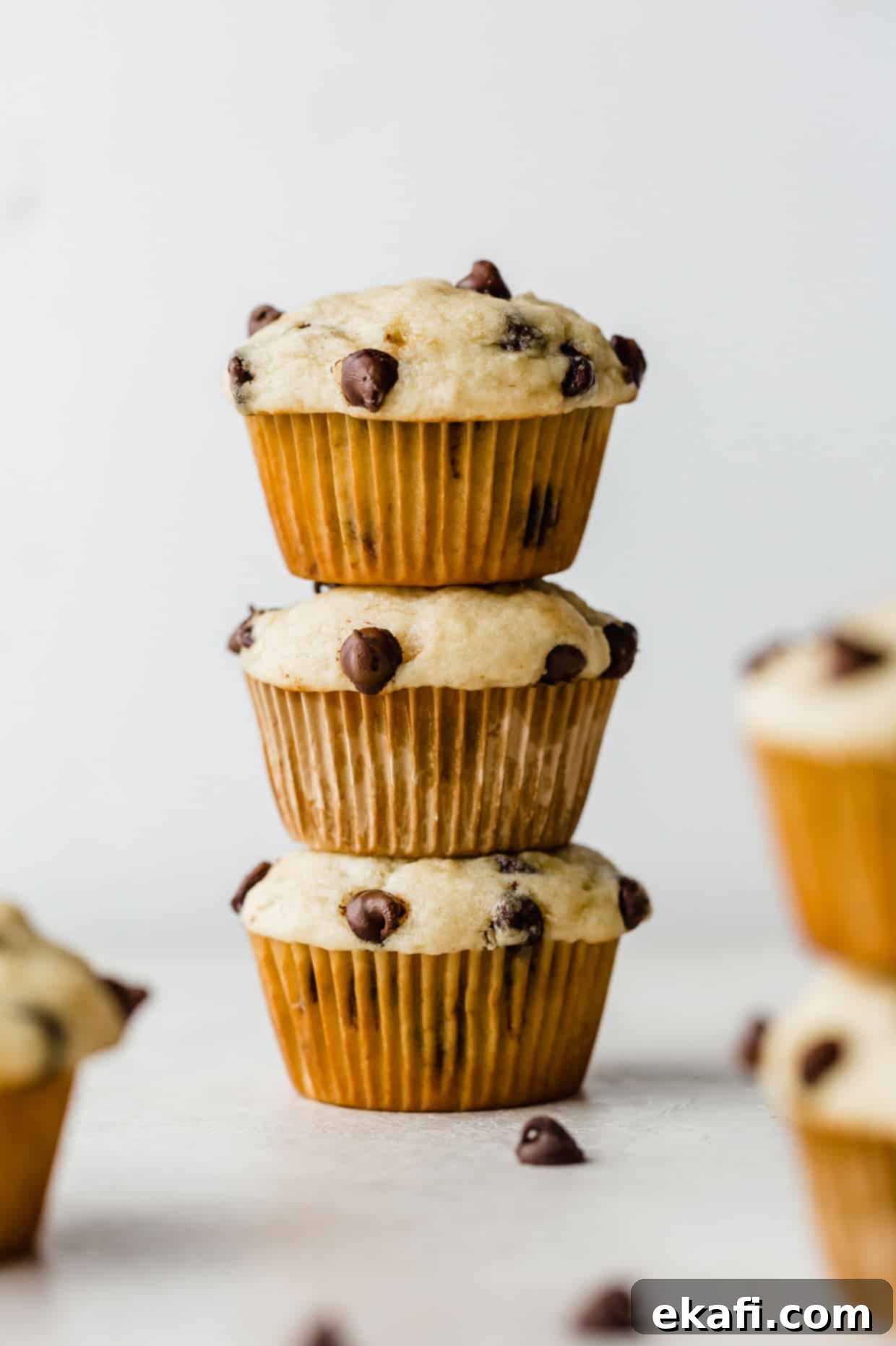 Velvet Banana Chocolate Chip Muffins 2 Three Buttermilk Banana Chocolate Chip Muffins stacked on top of each other against a white background.