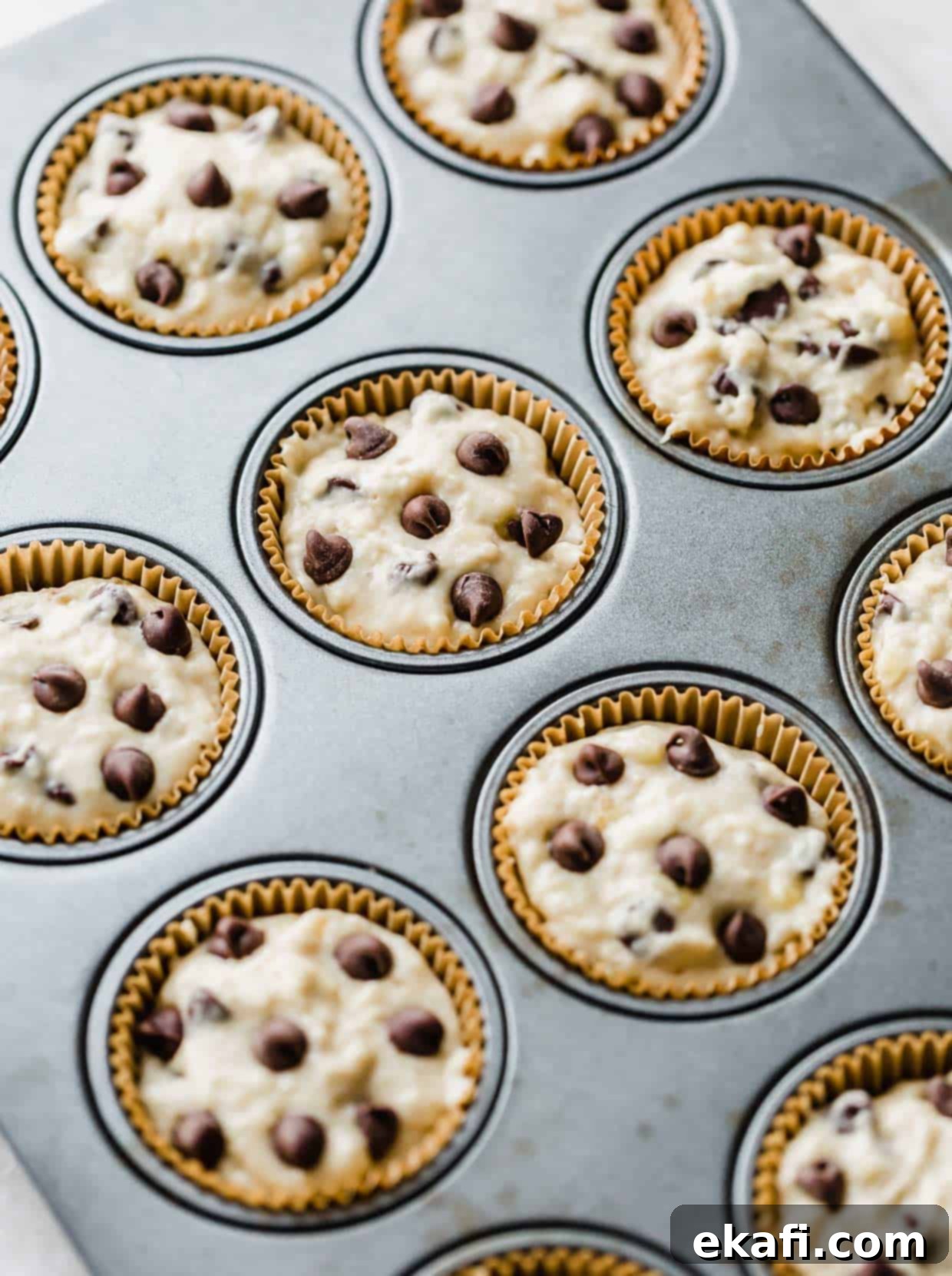Velvet Banana Chocolate Chip Muffins 6 Banana chocolate chip muffin batter in a muffin tin.