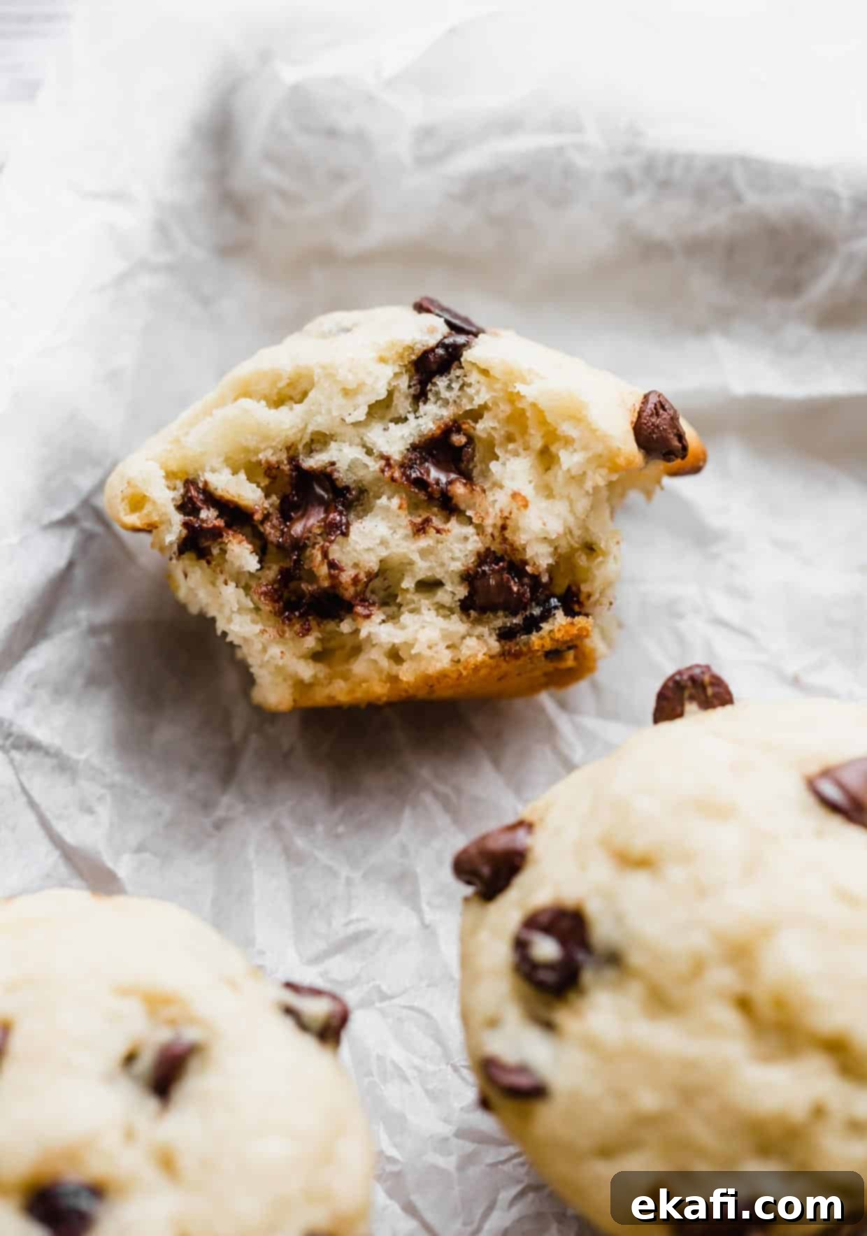 Velvet Banana Chocolate Chip Muffins 9 A Buttermilk Banana Chocolate Chip Muffin cut in half on a white parchment paper.