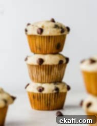 Velvet Banana Chocolate Chip Muffins 10 Three Buttermilk Banana Chocolate Chip Muffins stacked on top of each other against a white background.