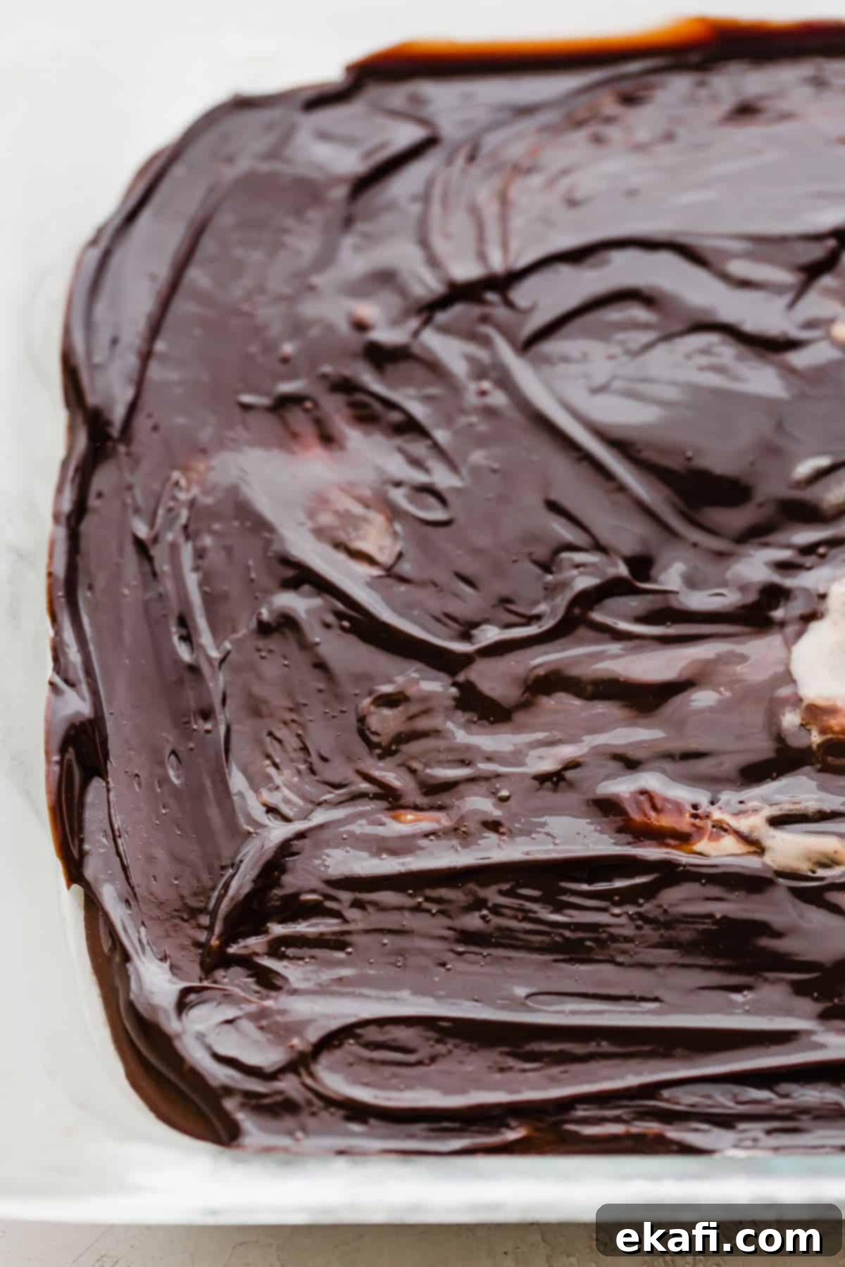 Frozen Oreo Indulgence 6 A close-up view of a thick, glossy layer of warm hot fudge spread perfectly over the frozen Oreo ice cream, creating an irresistible middle layer for the cake.