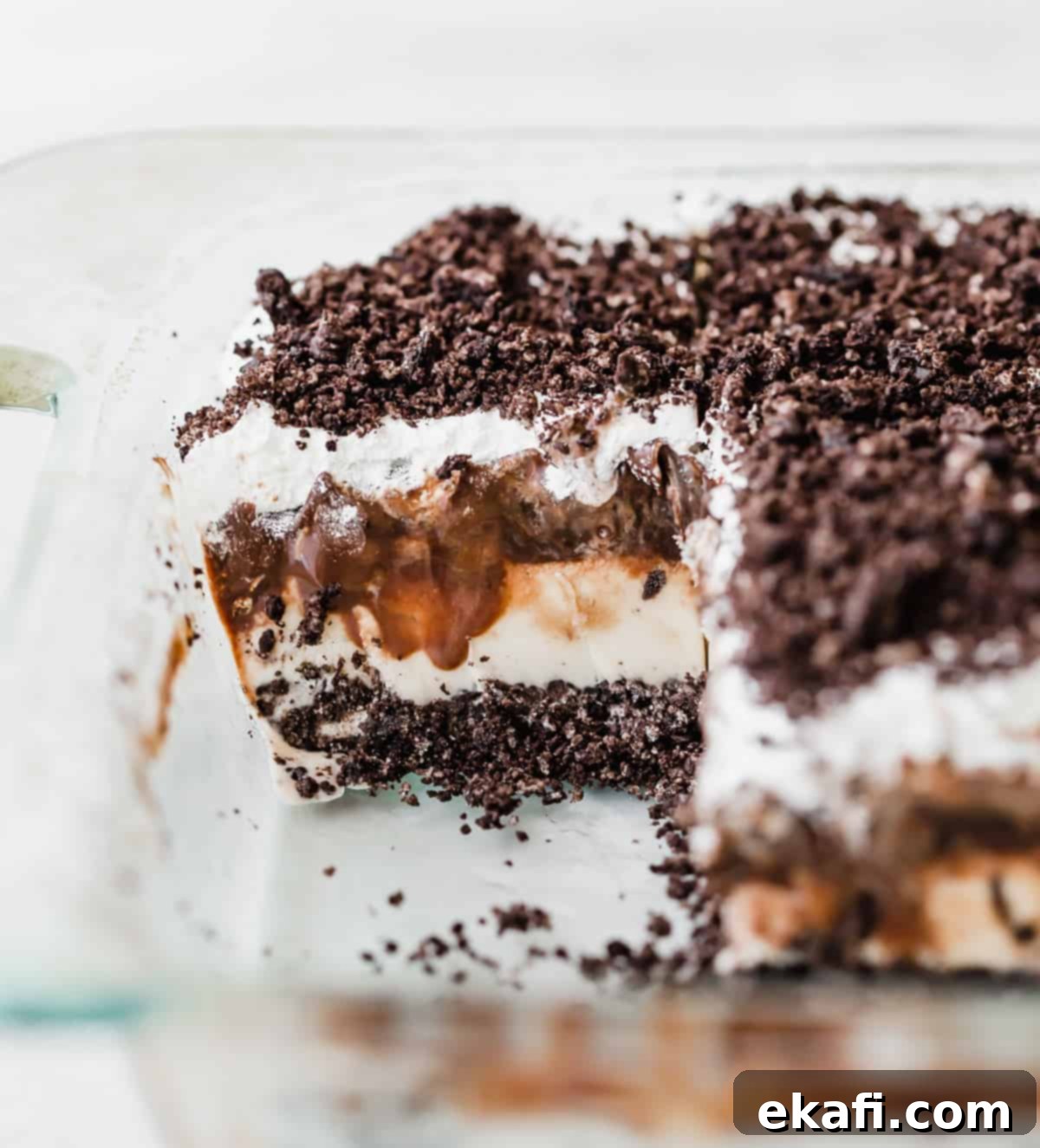 Frozen Oreo Indulgence 7 The fully assembled Oreo Ice Cream Cake, topped with white whipped topping and crushed Oreos, resting in a clear glass baking dish against a clean white background, ready to be frozen.