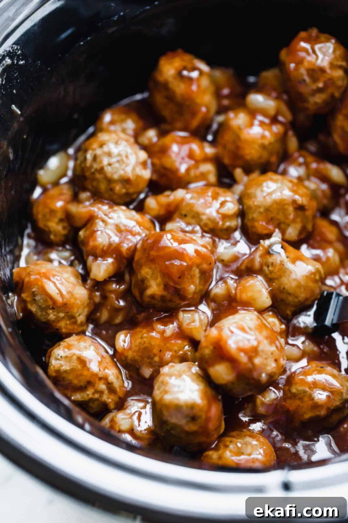 Sticky Pineapple BBQ Meatballs 6 A black slow cooker filled with simmering 3-ingredient BBQ Pineapple Meatballs, ready to be served.