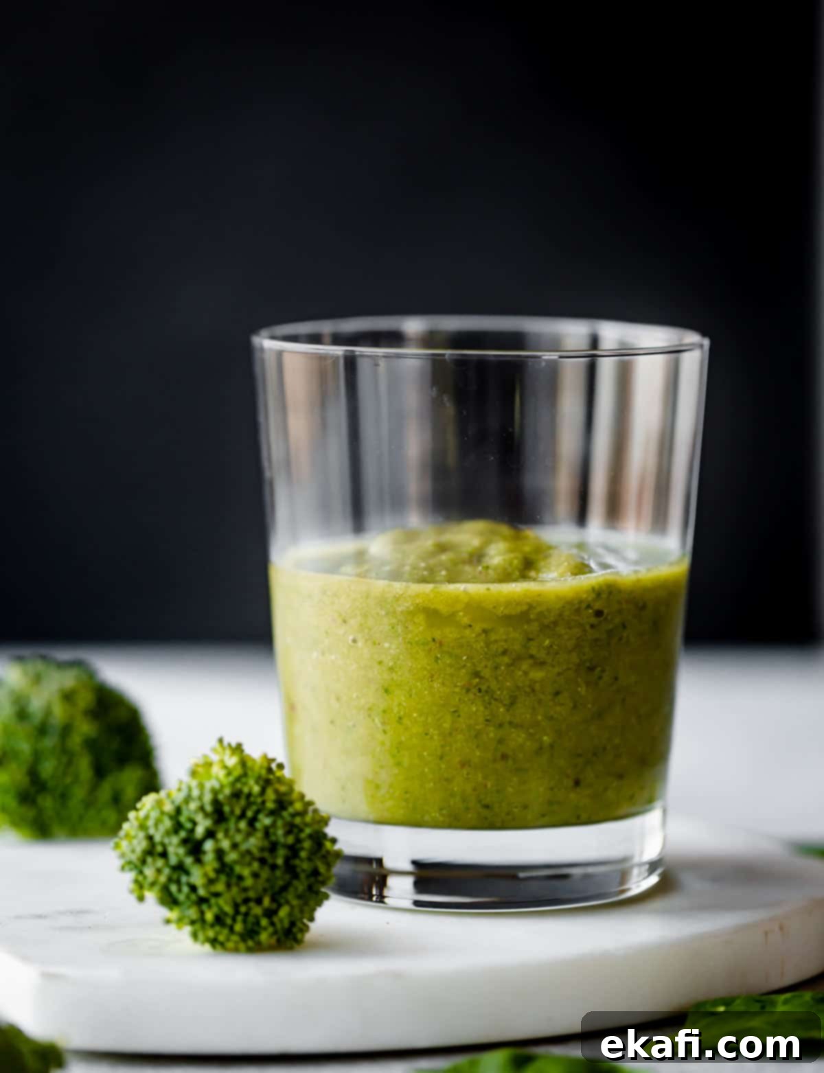 Green Power Smoothie 2 Broccoli Smoothie in a clear cup against a black background. A vibrant green smoothie.