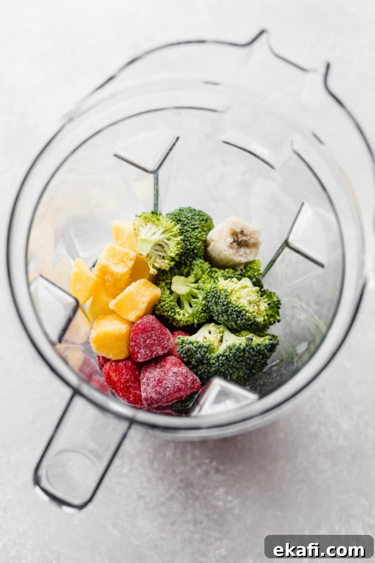 Green Power Smoothie 4 Strawberries, mango chunks, and broccoli in a blender, ready to be blended into a smoothie.