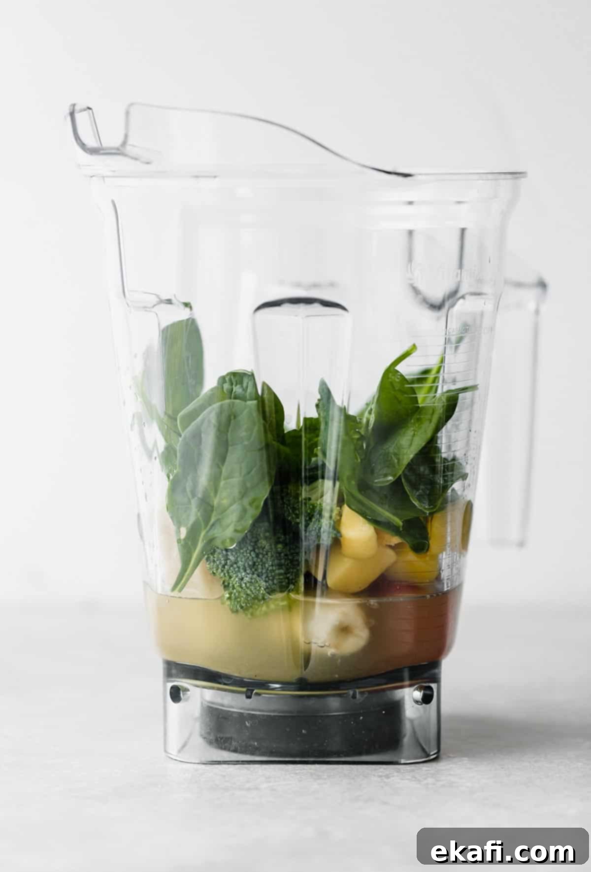 Green Power Smoothie 6 Broccoli smoothie ingredients, including fruits and greens, artfully arranged in a blender against a white background.