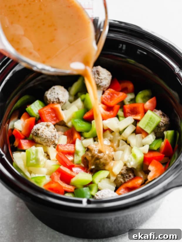 Tangy Sweet Slow Cooker Meatballs 7 Sauce being poured over the sweet and sour meatballs in a crock pot.