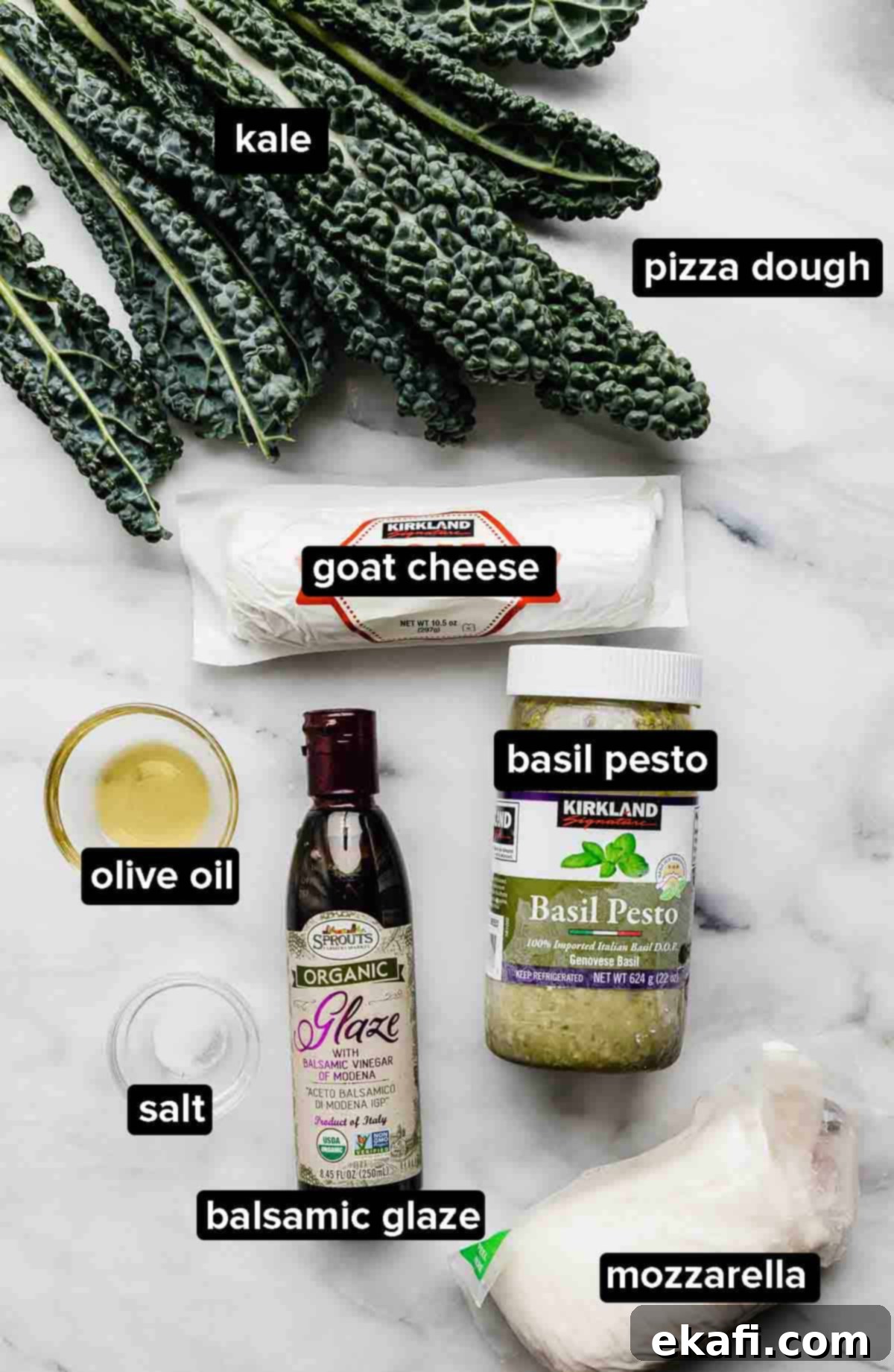 Citadel Pizza 3 A vibrant display of Kale Pizza ingredients including fresh kale, olive oil, basil pesto, creamy goat cheese, and shredded mozzarella, arranged beautifully on a white marble background.