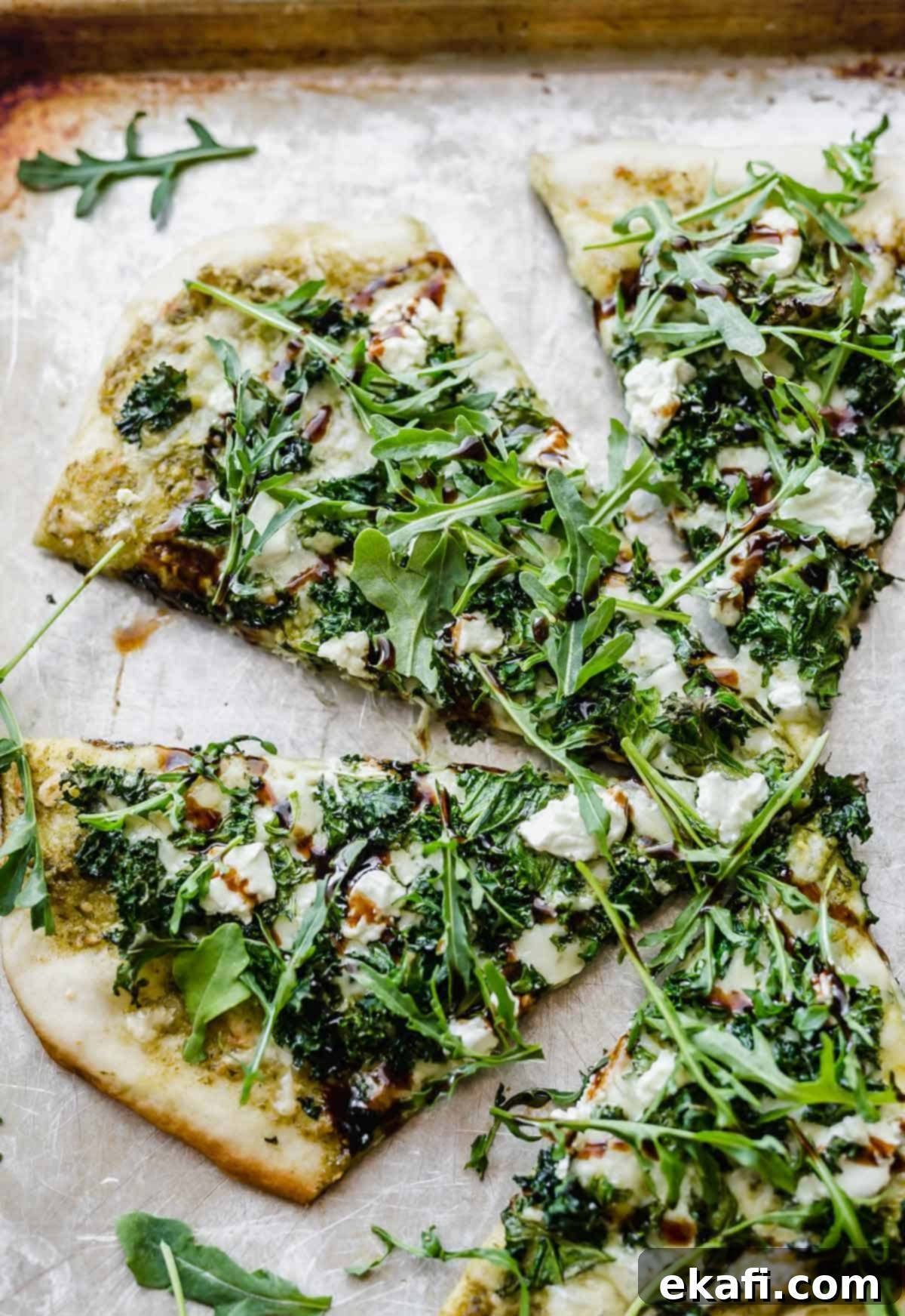 Citadel Pizza 5 Slices of delicious kale pizza, garnished with fresh arugula and crumbled goat cheese, ready to be enjoyed.