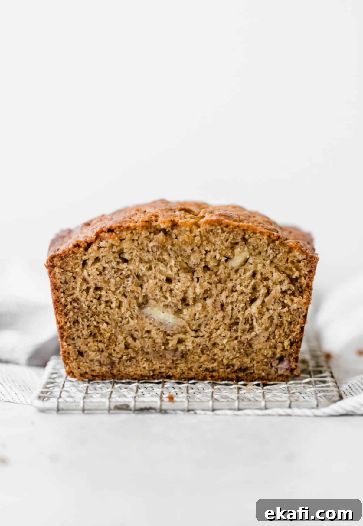 Irresistible Cinnamon Swirl Banana Bread 2 A load of Banana Bread that on a small wire rack against a white background.