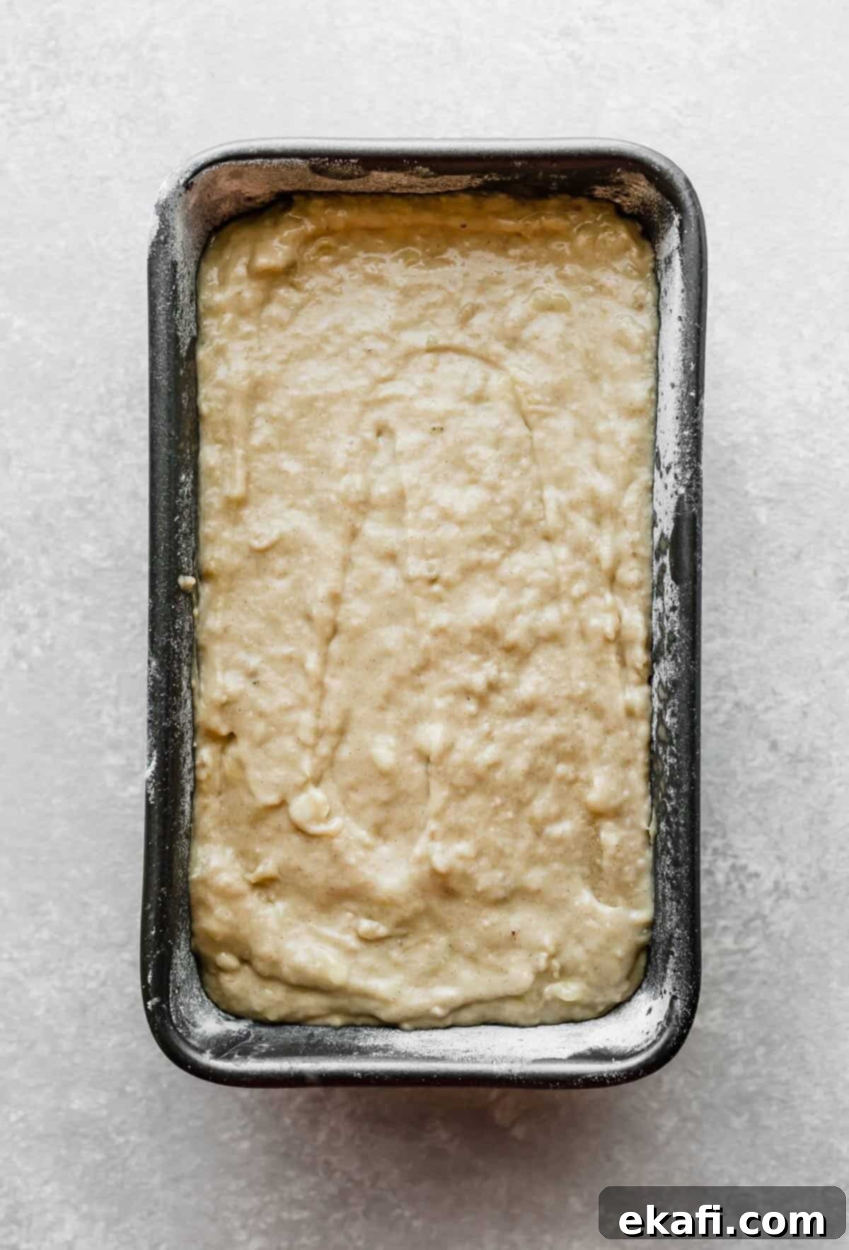 Irresistible Cinnamon Swirl Banana Bread 7 Banana bread batter in a grey bread pan on a light grey background.