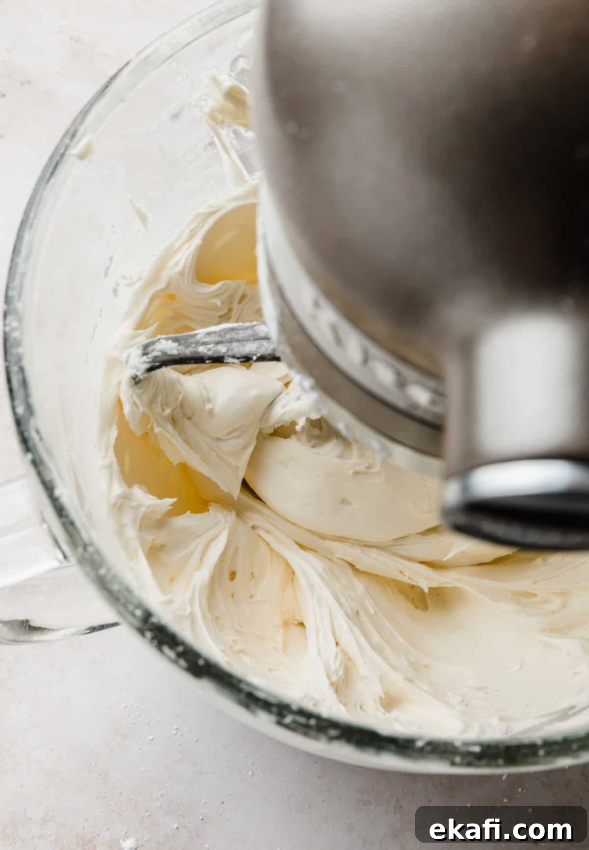Decadent Chocolate Buttercream 7 White frosting being mixed in a stand mixer bowl with a paddle attachment, prior to adding chocolate.
