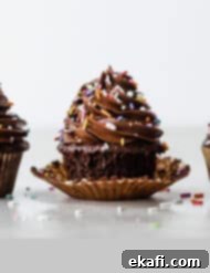 Irresistibly Rich Chocolate Cupcakes 11 Three chocolate cupcakes lined up side by side on against a white background.