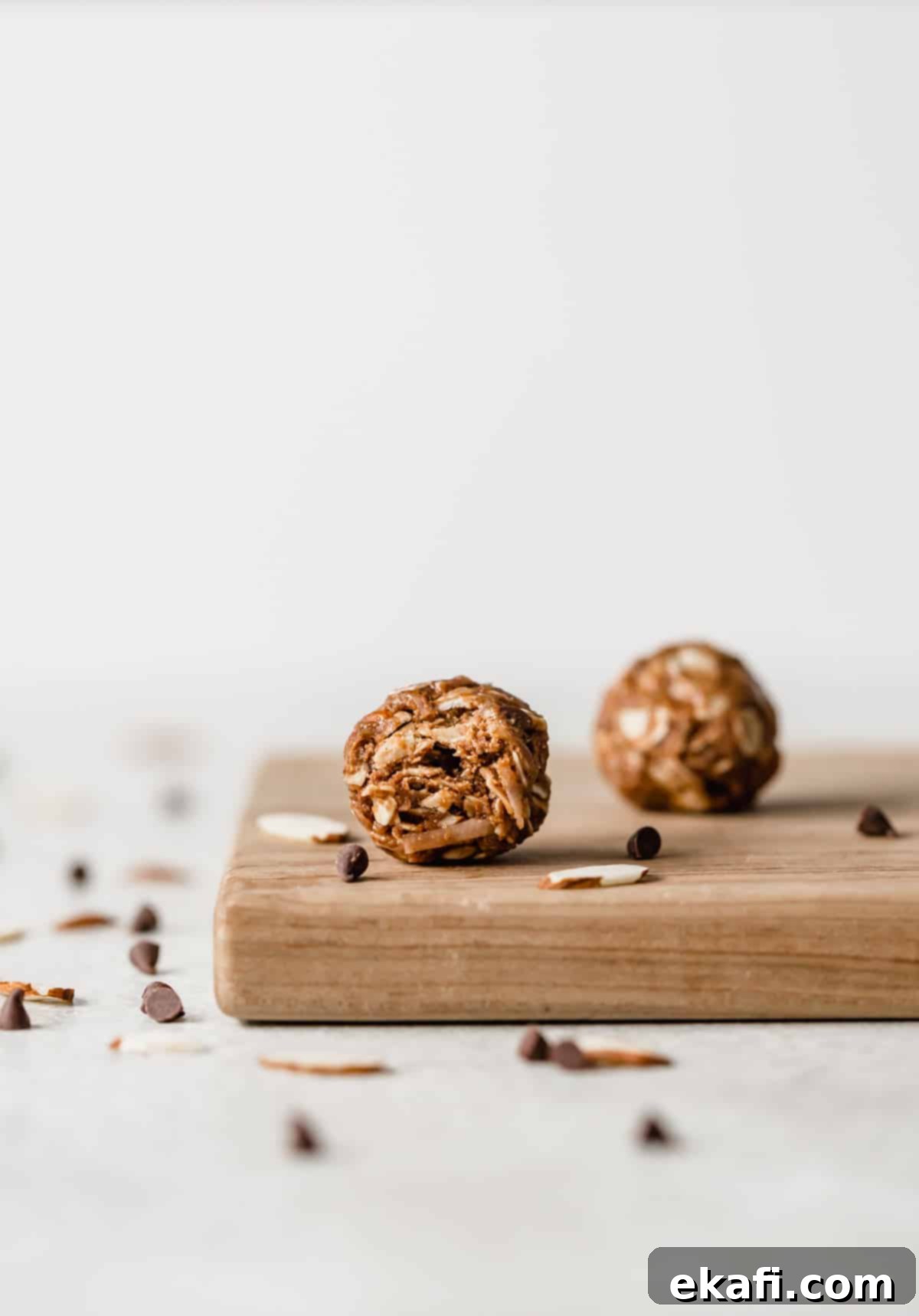 Μπάλες Πρωτεΐνης με Αμύγδαλο Joy 7 An Almond Joy Protein Ball on a wood cutting board with a bite taken out of it.