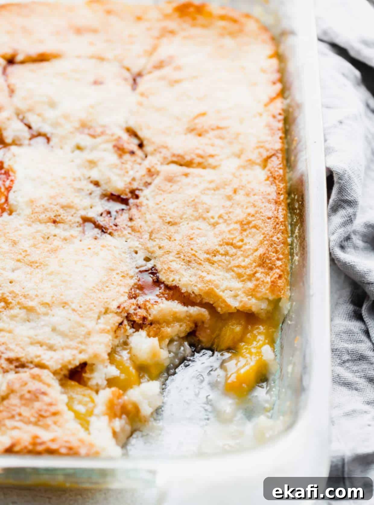 Παραδοσιακό Κομπλέρ Ροδάκινο 6 Εύκολο Peach Cobbler ψημένο σε γυάλινο ταψί με ένα κομμάτι να έχει αφαιρεθεί.