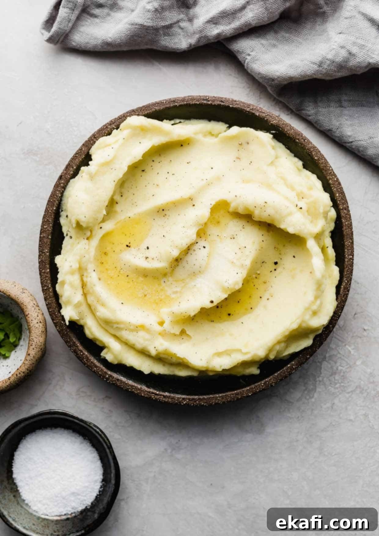 Velvety Half-and-Half Potatoes 2 Mashed Potatoes on a black plate topped with melted butter.