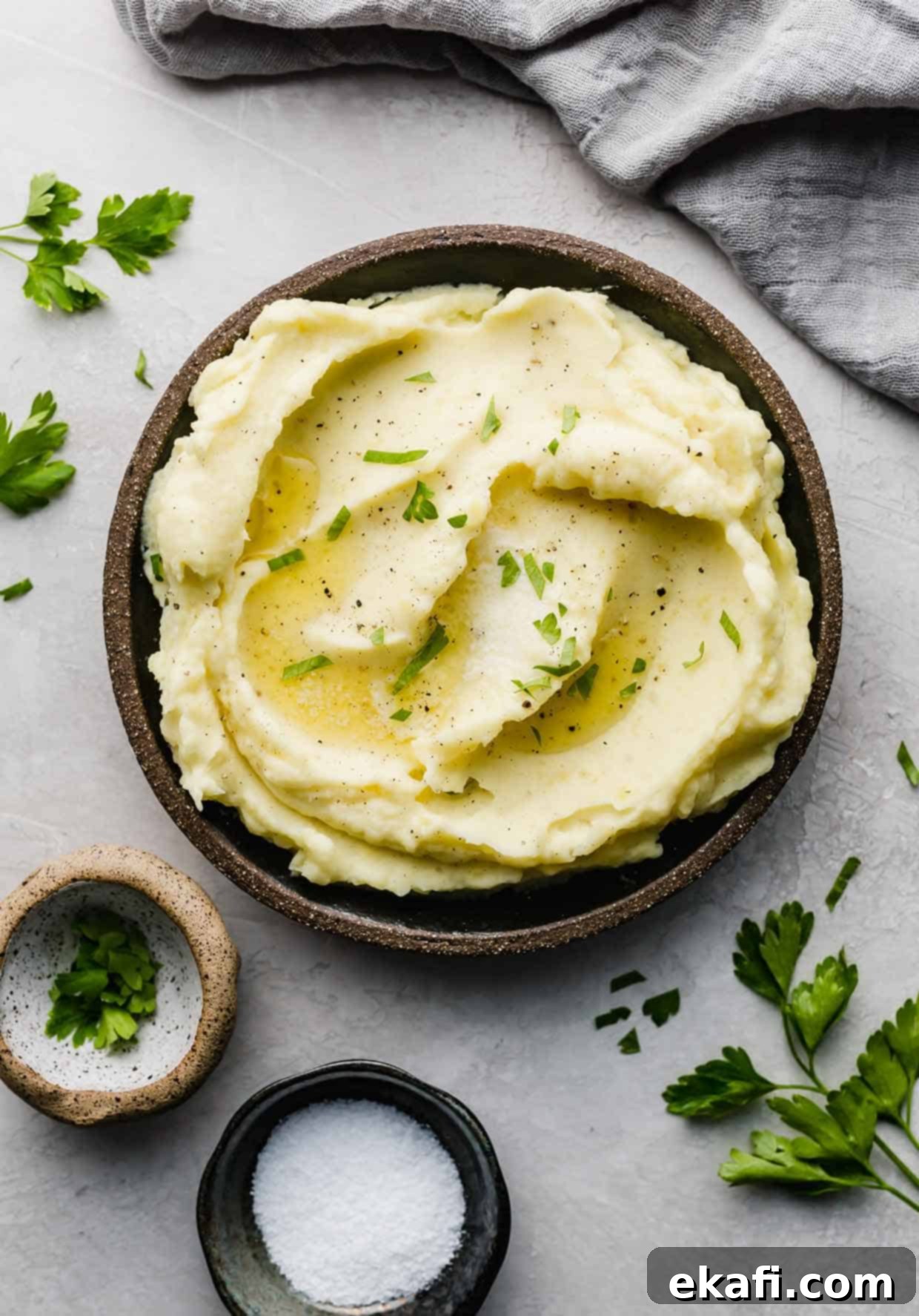 Velvety Half-and-Half Potatoes 6 Swirled homemade mashed potatoes on a black plate topped with fresh chopped parsley.