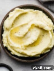 Velvety Half-and-Half Potatoes 7 A black rimmed plate filled with Homemade Mashed Potatoes made with half and half and butter.