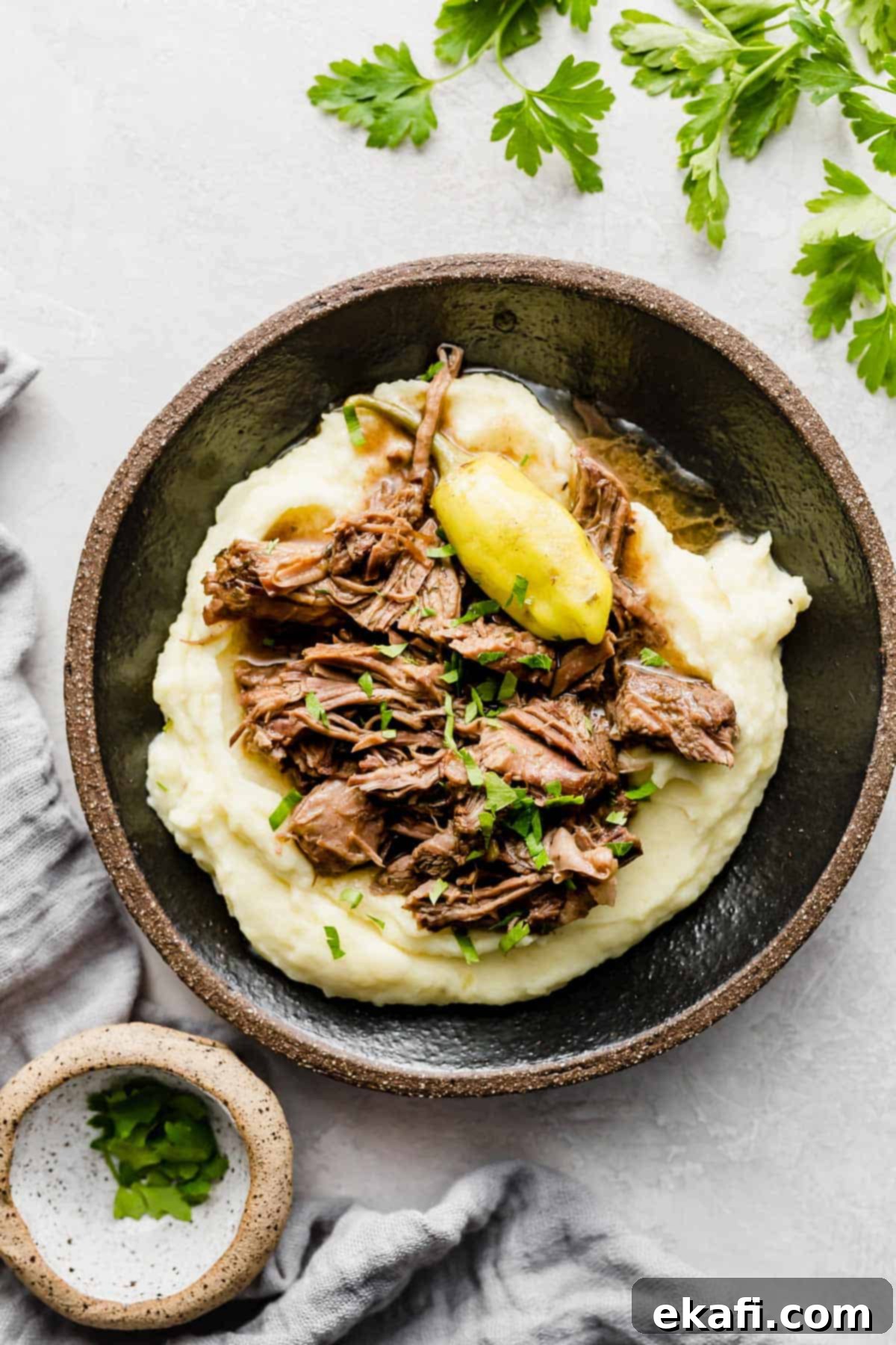 Southern Comfort Mississippi Pot Roast 2 Mississippi Pot Roast overtop white mashed potatoes on a black plate.