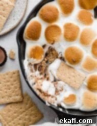 Ντιπ Σμόρες Ρήσης 8 Reese's S'mores σε μαντεμένιο τηγάνι με κράκερ να βουτάει σε marshmallows και κύπελλα φυστικοβούτυρου.