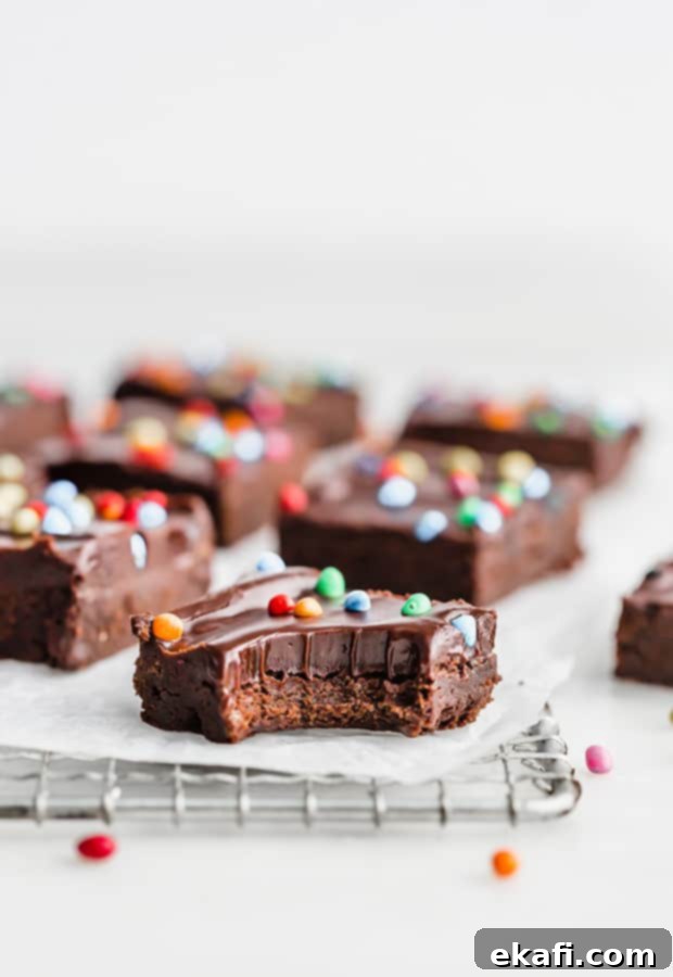 Stardust Brownies 2 A fudgy homemade Cosmic Brownie with a bite taken out of it, showing the dense interior and chocolate ganache with sprinkles.