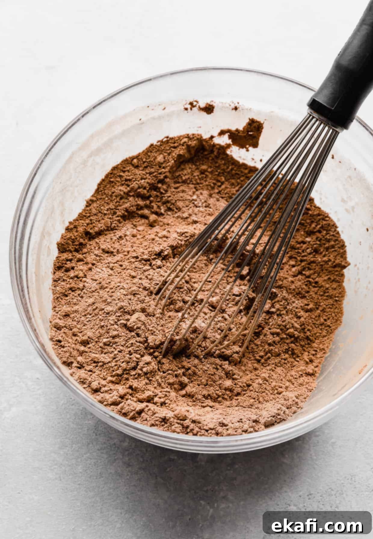 Stardust Brownies 8 A light brown colored dry ingredients (flour, cocoa, cornstarch, salt) in a glass bowl, being whisked together.