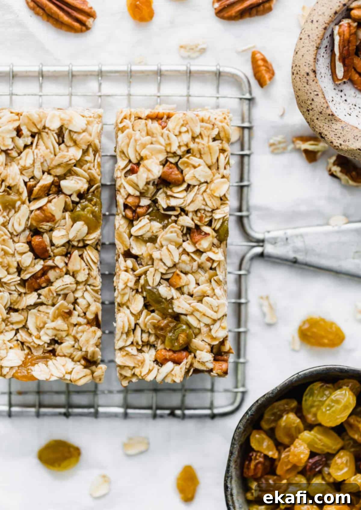 Μπάρες Γκρανόλα Βρώμης Σταφίδας 2 Oatmeal Raisin Granola Bars with pecans on a wire rack against a white background.