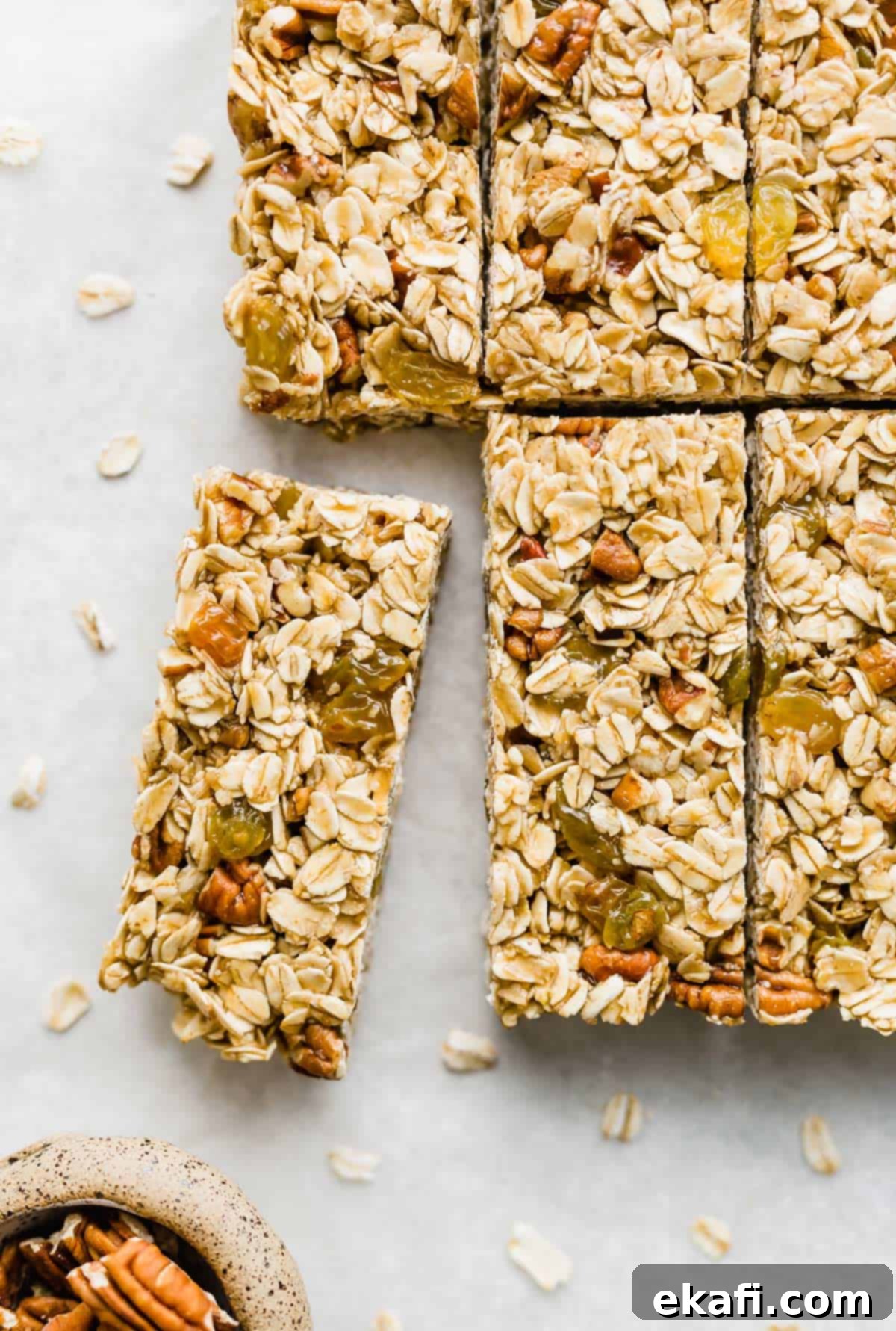 Μπάρες Γκρανόλα Βρώμης Σταφίδας 8 Homemade granola bars filled with rolled oats, nuts, and golden raisins, cut into bars on a white background.