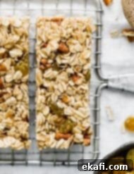 Μπάρες Γκρανόλα Βρώμης Σταφίδας 10 Homemade granola bars with oatmeal and raisins and nuts sliced into bars on a wire rack, with golden raisins scattered around.