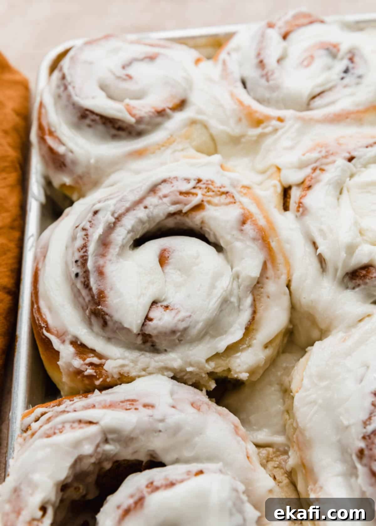 Delicious Homemade Cinnamon Rolls 13 Large cinnamon roll covered in white frosting on a baking sheet.