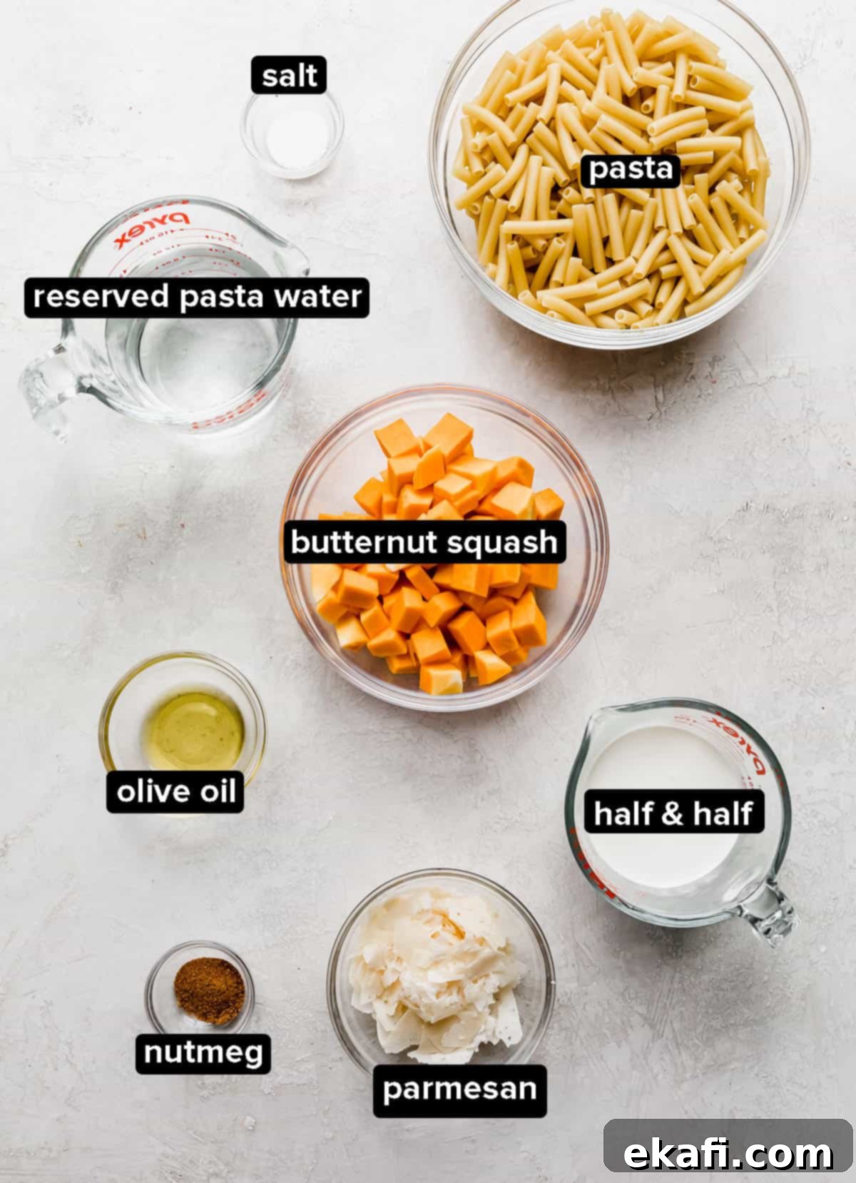 Velvety Butternut Squash Pasta 3 Roasted Butternut Squash Pasta ingredients laid out on a clean white background, showcasing fresh butternut squash, half & half, nutmeg, parmesan, and pasta.
