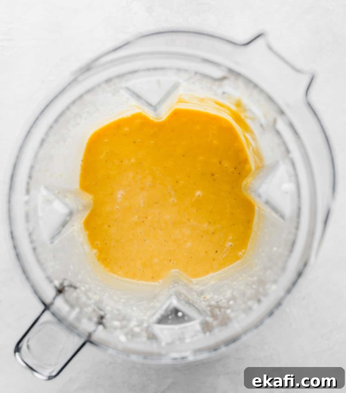 Velvety Butternut Squash Pasta 6 Pureed Roasted Butternut Squash Pasta sauce in a blender on a white background, showing its smooth, vibrant orange texture.