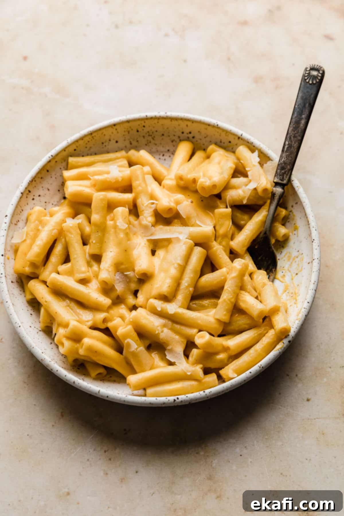 Velvety Butternut Squash Pasta 8 A white plate filled with perfectly coated ziti noodles in a vibrant butternut squash pasta sauce, ready to be served. The sauce is thick and inviting.