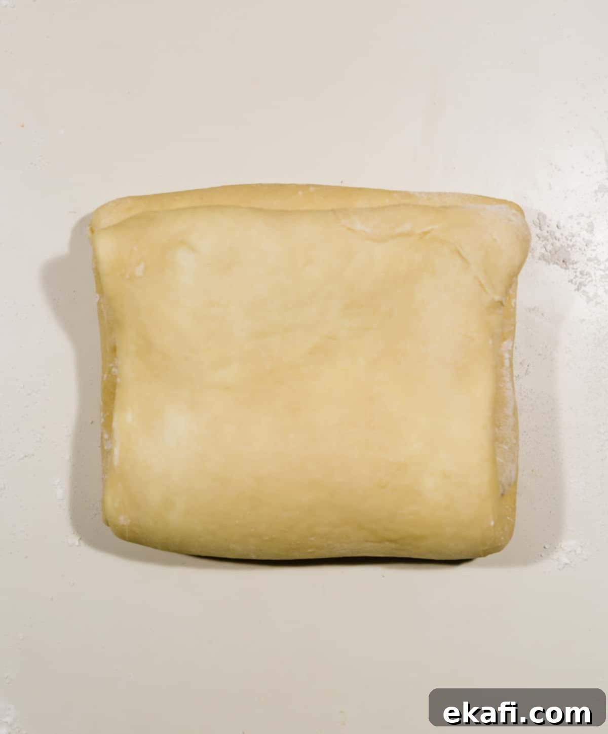 Pillowy Flaky Brioche 14 A perfectly squared parcel of flaky brioche bread dough on a pristine white countertop, ready for chilling.
