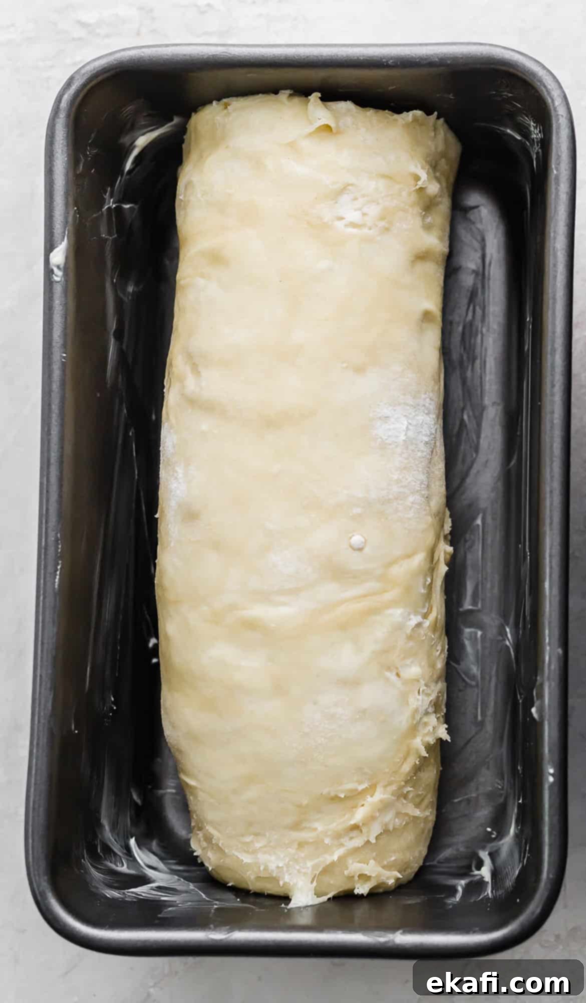 Pillowy Flaky Brioche 15 Brioche bread dough, expertly rolled up into a log and placed in a bread pan, ready for its final proof.