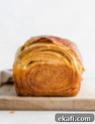 Pillowy Flaky Brioche 17 White flaky brioche bread loaf on a cutting board against a white background, highlighting its delicate crumb.